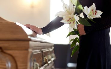 woman with lily flowers and coffin at funeral